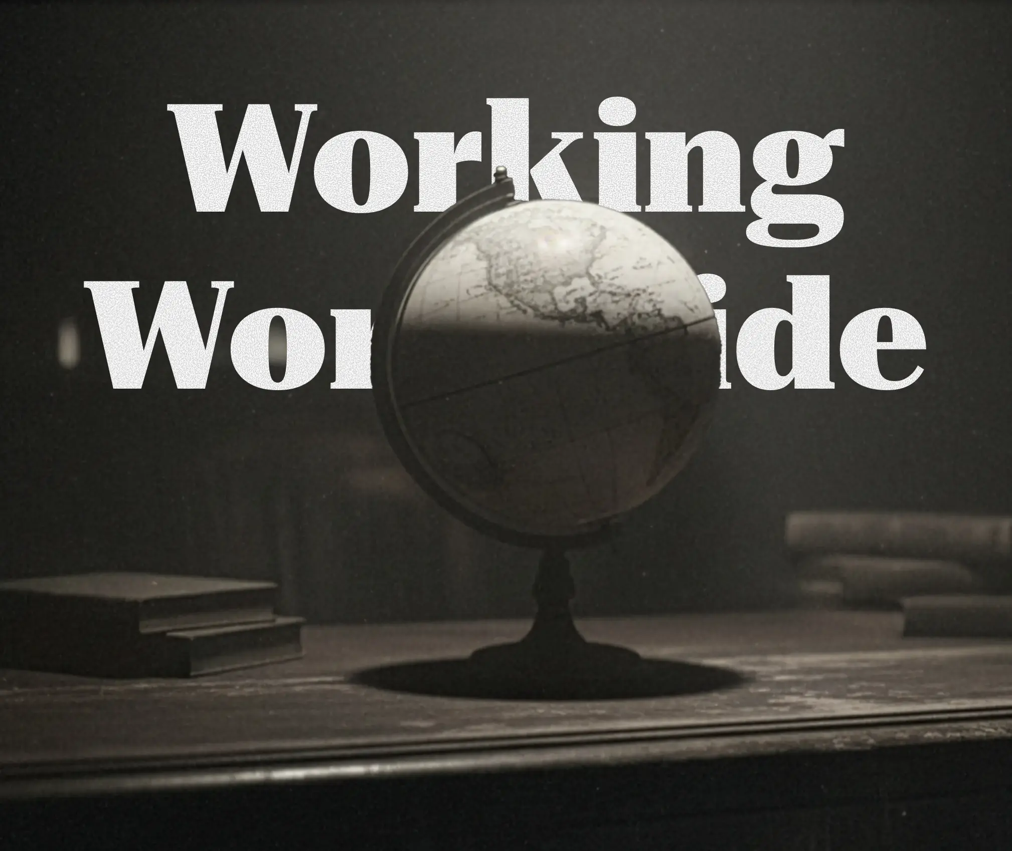 A vintage globe and books on an old wooden desk under soft light
