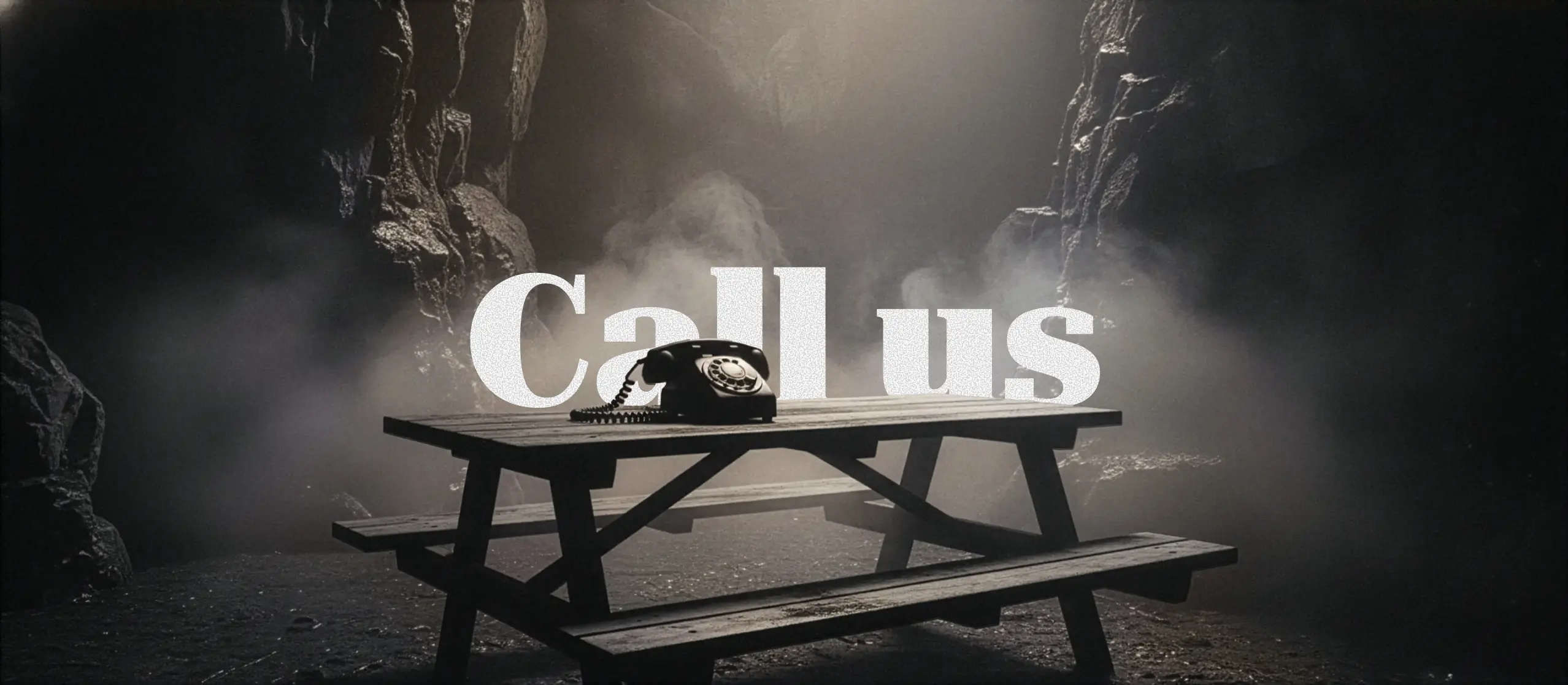 A vintage rotary phone on a wooden table in a dark, misty cave